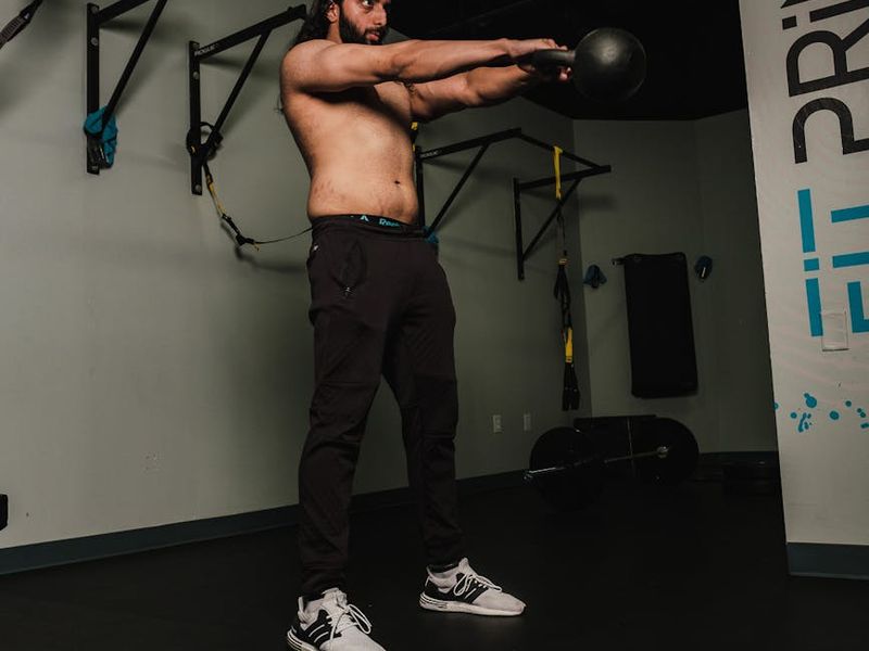A man performing a focused strength exercise with kettlebell.