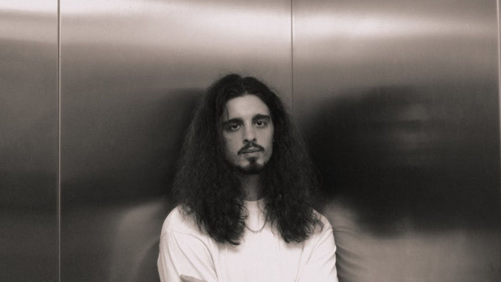 Man standing in a thoughtful pose in a minimalist gym setting.